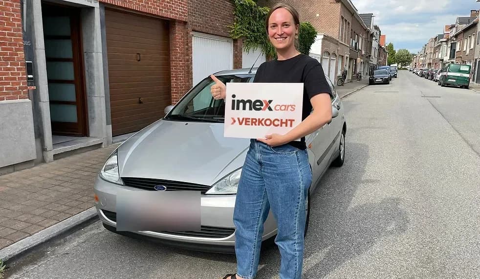 Verkoper met Imex Cars ‘VERKOCHT’ bord bij verkochte wagen, verkoop je auto in België