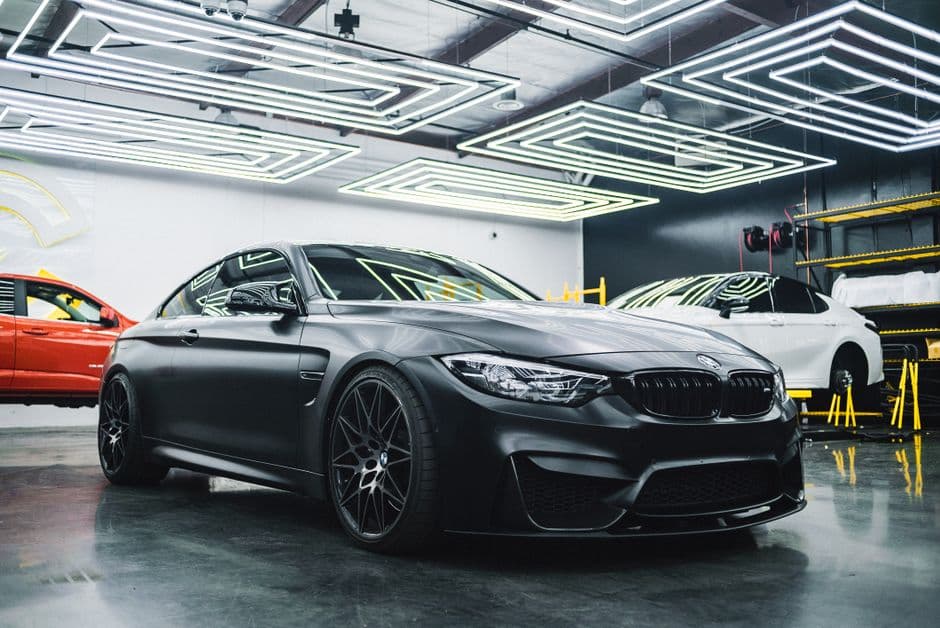Mat zwarte BMW-coupé in een verlichte werkplaats