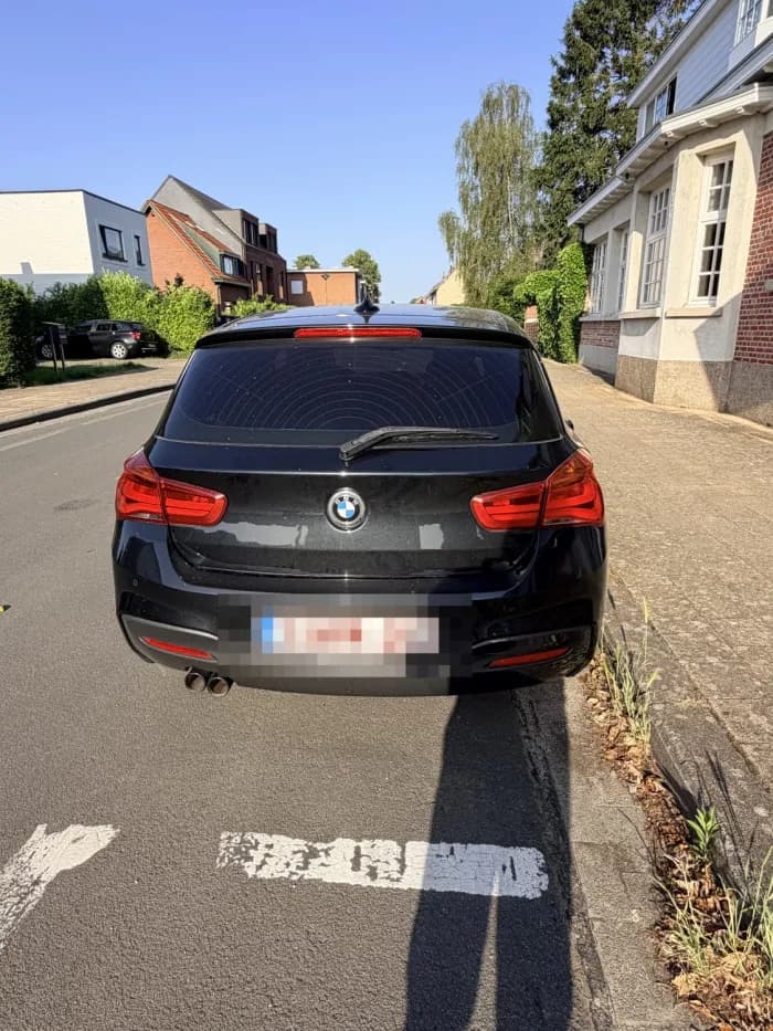 Zwarte BMW 1 Serie van achteren op straat, aangemeld bij Imex Cars